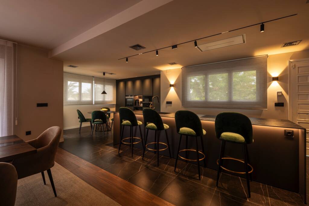 Cocina con isla e iluminación empotrada, diseño de interiorismo en Valencia con materiales oscuros, texturas elegantes y distribución funcional.