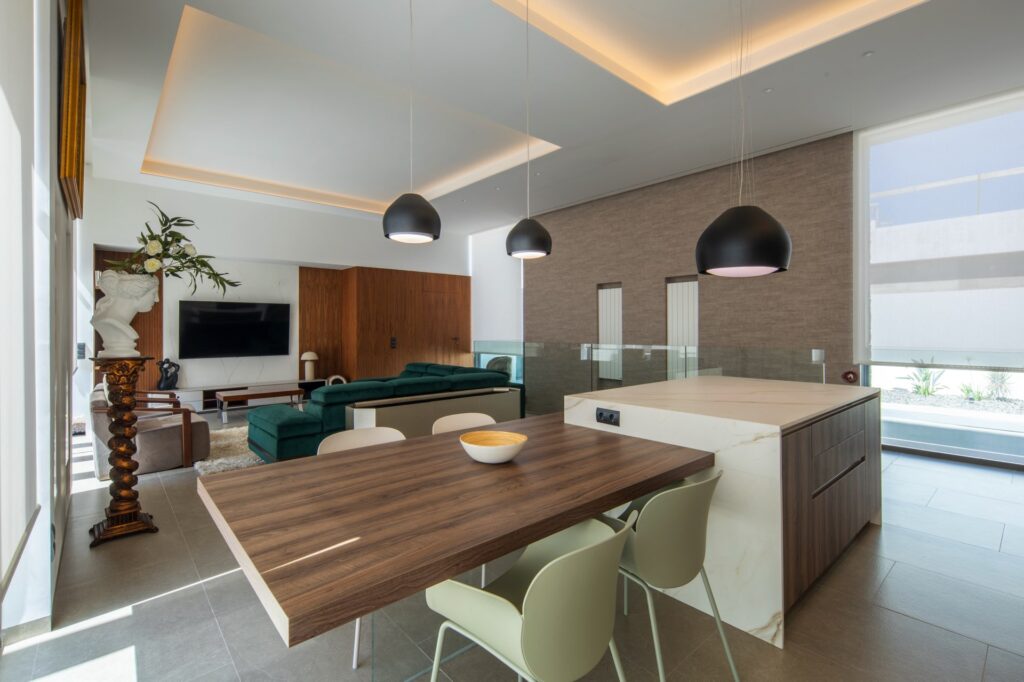 Cocina abierta con isla y mesa integrada en madera, parte de un proyecto de interiorismo en Valencia con líneas limpias y materiales naturales.