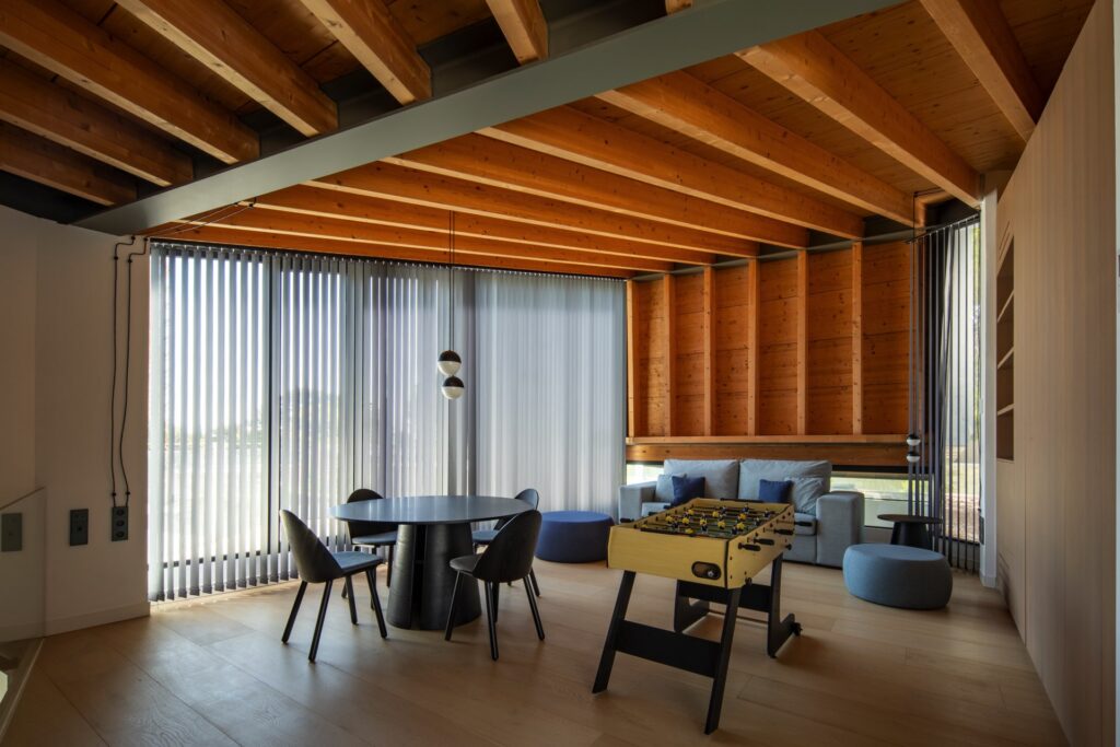 Zona de estar con techo de madera vista, diseño contemporáneo y elementos de ocio en un proyecto de interiorismo en Valencia.